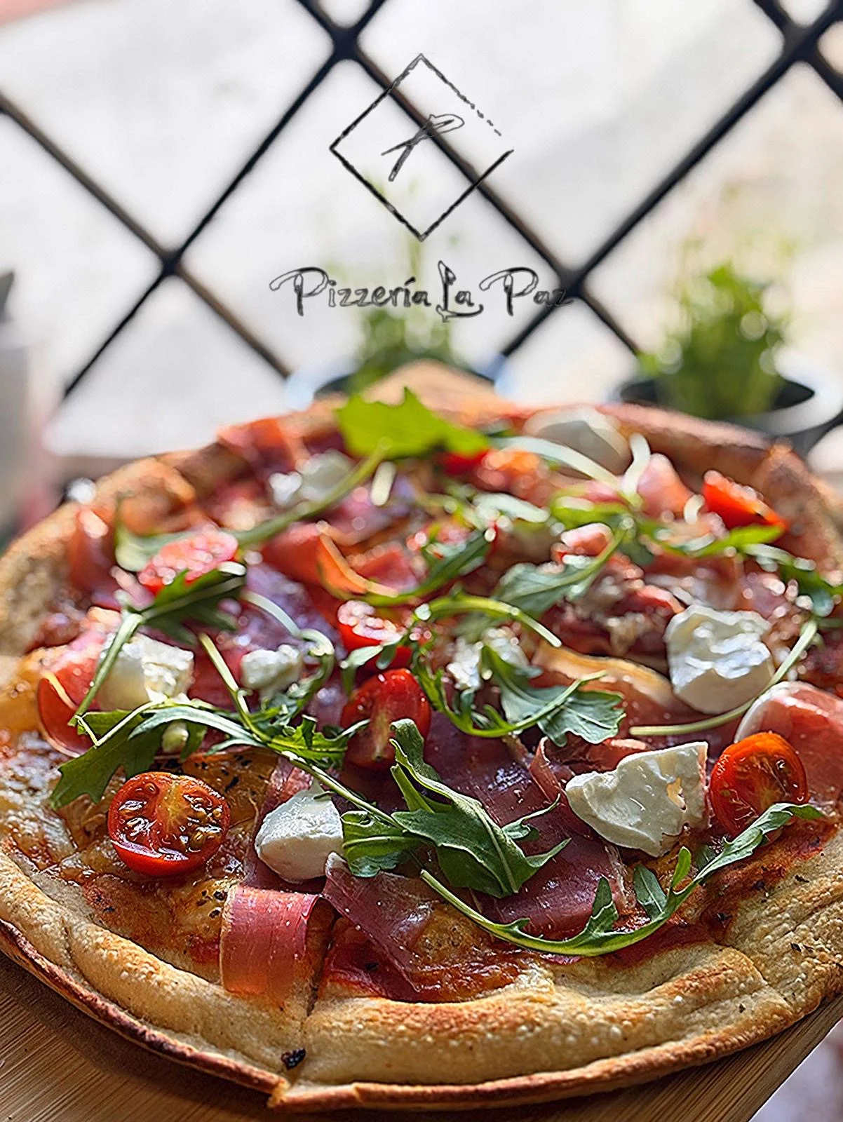 Pizza de Pizzería La Paz con rúcula, tomate y queso
